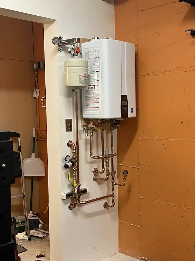 Plumbing technician inspecting water heater connections in Mandan